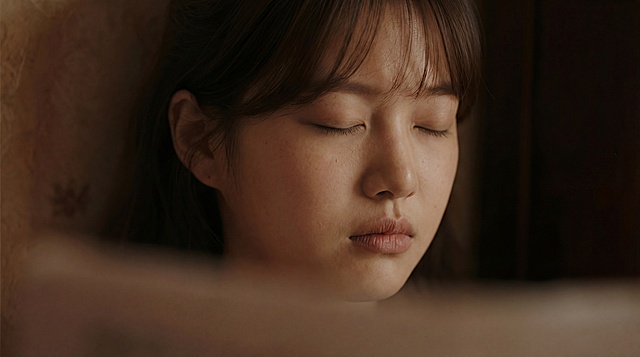 A cinematic close-up portrait of a young woman with fair skin and soft facial features, eyes closed, calm and introspective expression, subtle melancholy. Natural skin texture with visible pores and freckles, no retouching. 


Soft low-key lighting, warm directional light illuminating her face from the side, gentle highlights on the cheeks and nose, painterly shadows shaping the facial contours. Warm brown and muted red color palette.


Shallow depth of field, soft foreground blur partially obscuring the frame, background softly out of focus. Intimate, quiet, solemn atmosphere.


Shot on a cinema camera, 35mm film look, realistic lens behavior, natural light simulation, soft contrast, organic highlights, subtle film grain. Ultra-realistic, photorealistic cinematic still, period drama art film aesthetic.low quality, worst quality, low resolution, blurry, out of focus, jpeg artifacts, pixelated, oversharpened, noise, aliasing,
bad anatomy, bad face, distorted face, asymmetrical face, malformed features, extra face, duplicate face, deformed head, wrong proportions,
smooth skin, plastic skin, waxy skin, airbrushed, beauty filter, porcelain skin, doll-like face,
anime, manga, cartoon, illustration, digital painting, concept art, fantasy style, 3d render, cgi, unreal engine, game character,
overexposed, underexposed, harsh lighting, flat lighting, neon colors, oversaturated, high contrast, HDR, artificial lighting,
wide angle distortion, fisheye, extreme perspective, cropped head, cut off face, awkward framing,
modern clothing, contemporary fashion, jeans, t-shirt, hoodie, modern accessories, glasses, heavy makeup,
smiling, laughing, open mouth, exaggerated expression, seductive pose,
text, watermark, logo, signature, frame border