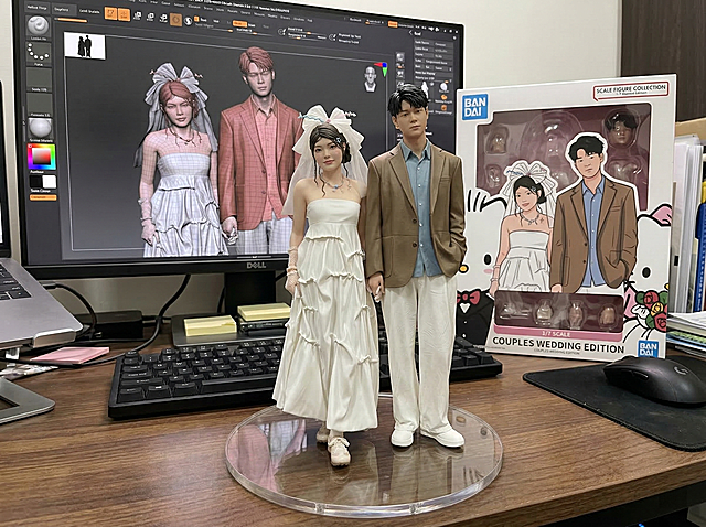 基于参考图中的情侣形象，制作1/7比例的写实风格双人商业手办，手办放置在电脑桌上，搭配无文字的圆形透明亚克力底座；电脑屏幕展示该手办的ZBrush建模过程，屏幕旁放置带有该情侣原版艺术插图的BANDAI风格玩具包装盒，包装为二维平面插图设计，所有人物相关元素与参考图严格一致