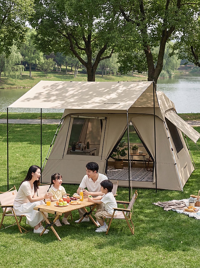基于参考图，重新生成8K高清写实商业摄影作品，主体为卡其色天幕帐篷二合一，一体式自动帐篷搭配延伸大天幕，带有网纱门和全景窗，由金属支架支撑。帐篷放置在城市近郊公园的翠绿草坪上，背景是成荫绿树与平静湖面，晴朗白天的柔和自然光，树叶光影投射在天幕和草坪上。前景是年轻东亚四口之家，父母带着一对儿女，围坐在折叠桌椅旁野餐，人物形象自然生活化无AI感，穿着浅色系休闲服饰，互动氛围温馨。帐篷内可见小边桌、绿植和地垫，底部展示赠送的防潮垫。整体风格清新治愈、松弛慵懒，ins风户外美学，突出产品完整形态与家庭露营使用场景，细节清晰，无AI痕迹