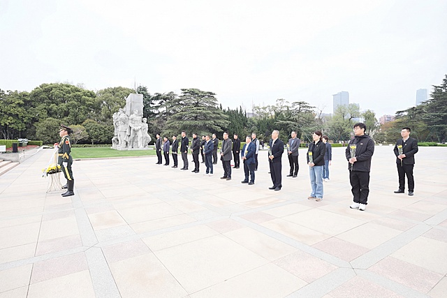 给图片最右边最后一位穿黑色西装的男士，也添加一束和前面人一样的黄色花束，保持整体画面风格一致，自然真实