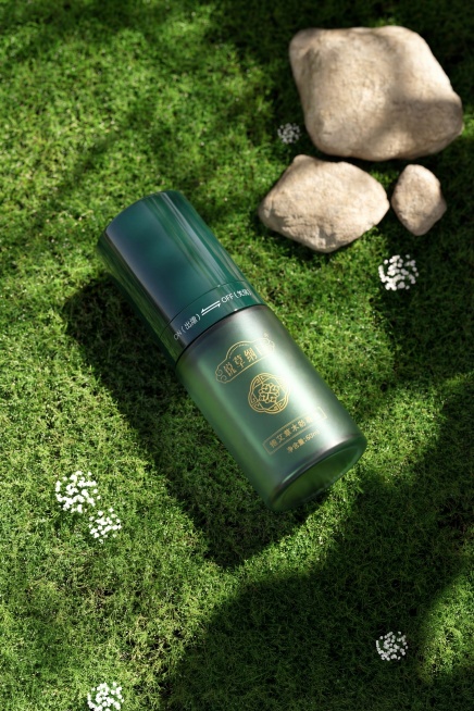 将图中的绿色护肤精油瓶替换到草地背景图中，保持原有产品的物理结构、尺寸和品牌文字Logo完全不变，整体质感更加高级。光影匹配：根据背景光源从右上方照射，在瓶身生成对应的受光面和背光面，在左下方自然投射预览效果