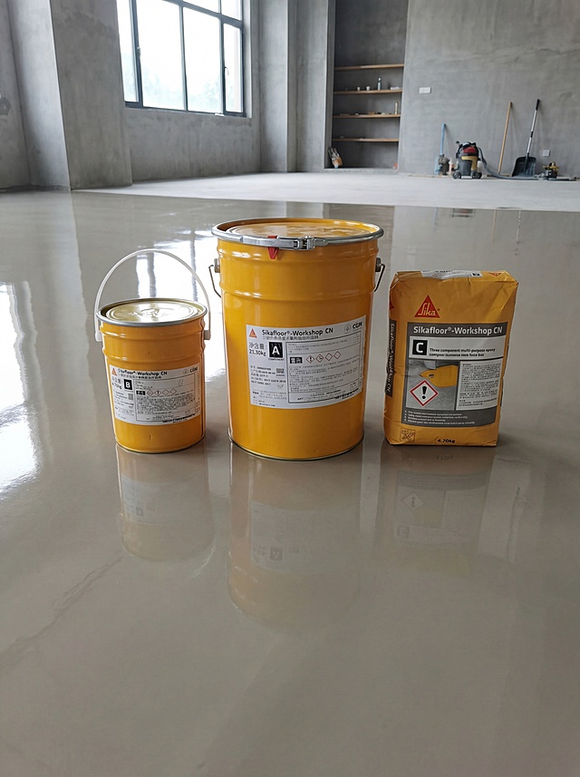 Sikafloor®-Workshop CN三组份多用途环氧树脂地坪涂料放置在刚施工完成的平整环氧地坪上，展示产品应用效果，保留产品包装和文字完整，自然柔和光线体现地坪光洁和产品质感，商用装修场景，适配1688详情页应用展示，产品结构不变形，文字清晰可见