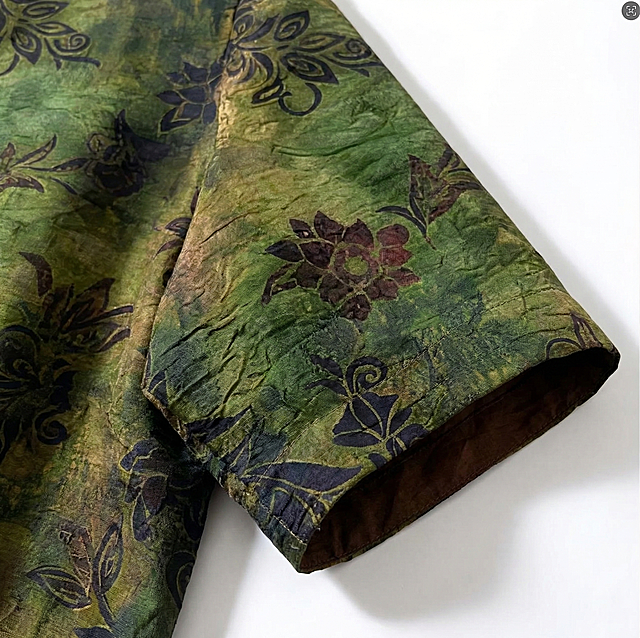 生成这件香云纱上衣的袖子局部特写图片，重点突出袖子部分的面料纹理和花色细节，保持原有的绿底植物花卉纹样和棕色内衬质感