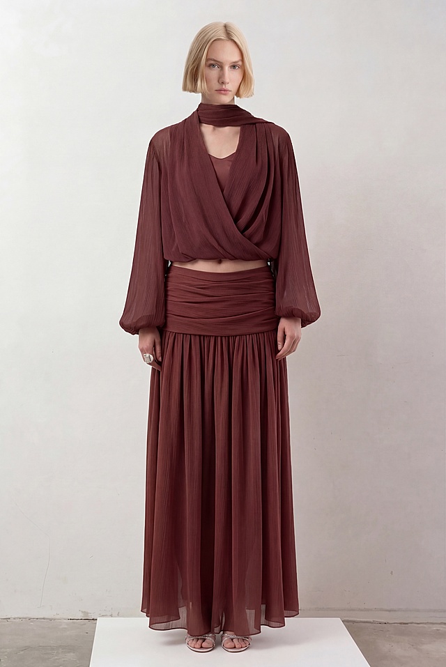 保持图一模特的姿势、金发短发发型、浅灰色背景、银色凉鞋和整体构图完全不变，仅将模特原有的紫棕色波浪纹针织套装替换为图二模特的红棕色挂脖围裹上衣+同色系褶皱大摆长款半裙套装，保持套装原有款式和面料不变，自然贴合模特身形，生成4K高清图片