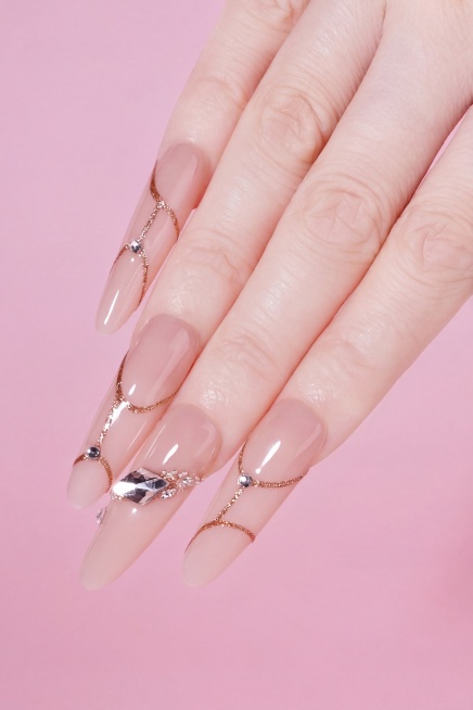 把手部皮肤P得更白皙透亮，不要改变指甲本身的颜色、美甲装饰和金色线条，保持原图整体构图、粉色背景和美甲样式不变预览效果