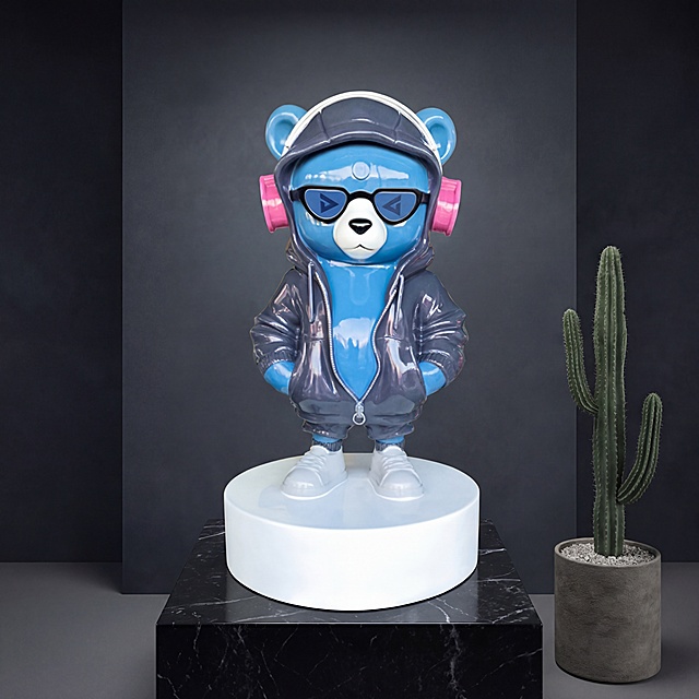 潮流小熊雕塑，站姿双手插兜姿势保持不变，主体蓝色熊身不变，耳机粉色耳罩不变，将原本紫色连帽套装更换为深灰色，鞋子保持浅灰色不变，保持整体亮面玻璃钢材质和物理结构绝对不变，严禁扭曲变形。放置在轻奢展厅黑色大理石展示台，深空灰渐变肌理背景墙，拉开景深。柔和漫射顶光，低对比度，阴影极淡柔和，画面干净高级，营造现代潮玩艺术氛围。三分法构图，平视全景观景角度。旁边点缀一小盆线条感仙人掌，空间更显生动。商业级4K，画面通透，严格锁定宽高比为1:1。西方面孔,金发,深眼窝,雀斑,杂乱房间,死黑阴影,硬光,乡村风,高对比度,欧美妆容,变形,扭曲,悬空,比例失调