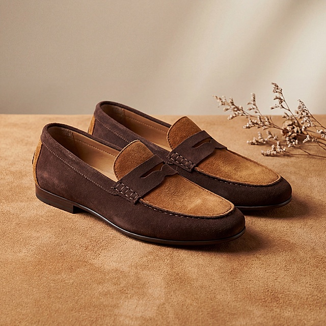 复古豆豆鞋，鞋身主体采用磨砂反绒皮材质，小面积拼接参考图中的翻毛皮皮革纹路，鞋子整体采用深浅两种材质搭配，颜色以棕色为主，保持鞋子物理结构不变，严禁扭曲塌陷。
鞋子平稳放置在同材质翻毛皮皮革上方，主体占画面70%，有真实接触阴影。
极简米色背景，拉开景深，营造轻奢优雅氛围。
柔和影棚漫射柔光，侧逆光勾勒材质纹理，低对比度，阴影极淡，画面明亮干净。
三分构图，微俯视视角。
旁边点缀一小枝干花装饰，打破单调。
商业高端时尚摄影，4K分辨率，极高材质细节。保持宽高比1:1。