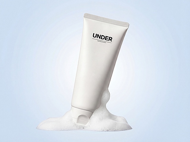 完全保留原洗面奶产品：白色软管，黑色文字UNDER，产品形状和文字100%不变。产品自然倾斜放置在画面中，背景是淡淡的蓝白渐变，产品底部周围增加少量自然的绵密泡沫，泡沫不遮挡任何产品主体和文字。整体风格清爽干净，浅淡柔和，适合电商展示，明亮柔和光影，保持原图比例，4K高清。负向提示词：修改产品外观,遮挡logo,泡沫过多,颜色过重,变形,水印,文字错误