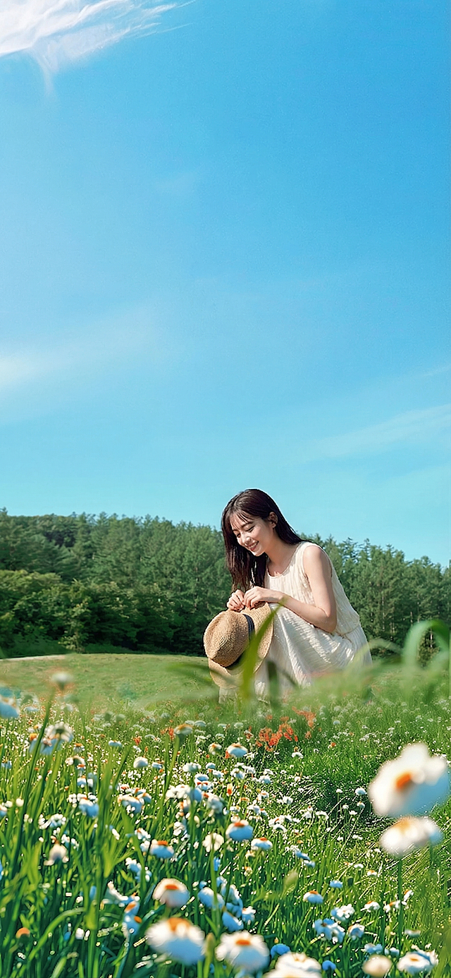 更改人物动作，替换人脸，保留原场景：蓝天白云下的雏菊花海，远处的绿色森林，人物穿着米白色连衣裙，手持草帽，整体风格清新自然