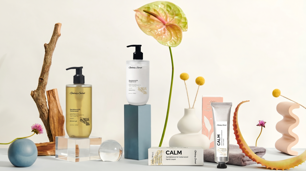 将原图场景中所有原有产品都去掉，原位替换为图2中的四款洗护产品（沐浴露、身体乳、护手霜和包装盒），将最左边的芦荟替换为檀木。
用新产品的真实物理结构完全覆盖原有产品区域，打破旧物轮廓束缚，保持新产品真预览效果