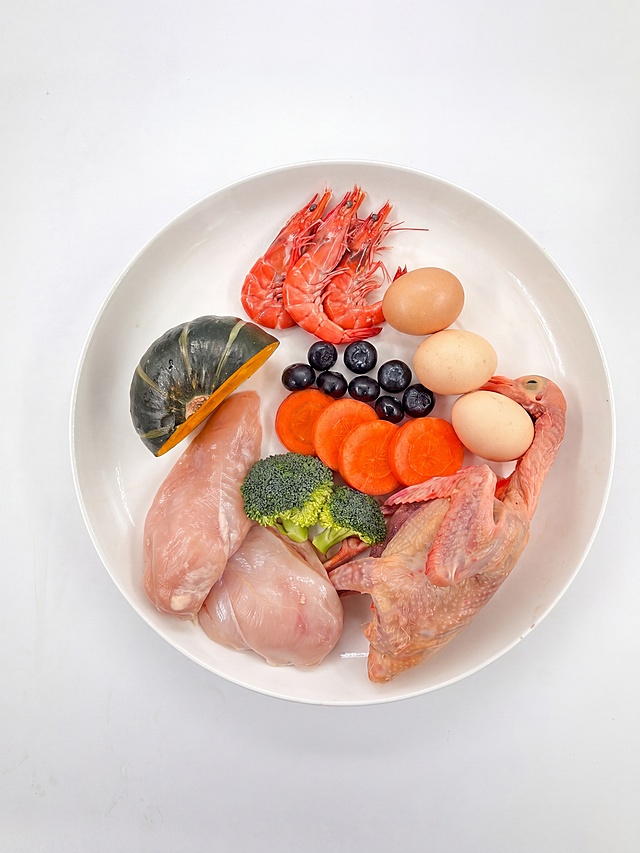 保留白色背景，强化食材新鲜感与食欲吸引力：鸡胸肉粉嫩微润、鲜虾橙红透亮带光泽、南瓜切面湿润金黄、乳鸽皮色粉嫩、西兰花翠绿饱满、胡萝卜片橙红鲜亮、蓝莓深紫透亮、鸡蛋壳自然哑光；专业棚拍光0，高光提亮表面水润感与金属光泽，微距级细节锐化（虾壳纹理、蔬菜切面水分、肉质纤维），整体呈现刚处理完毕的生鲜状态；构图与摆放完全保持原样