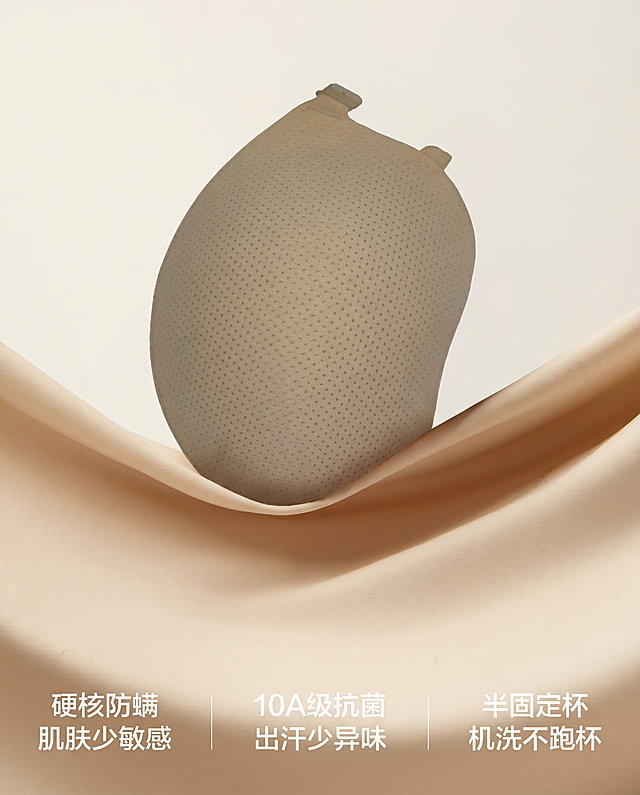 将原图画面中的圆形胸垫原位替换为图2(参考图)中的水滴形带网孔的胸垫，顶部有两个小连接扣。
用图2中物体的真实物理结构完全覆盖该区域，打破原图旧物的圆形轮廓束缚，保持原产品(图2)的真实比例，严禁挤压或变形。新产品需完美继承原图中旧物的摆放角度、镜头高度与透视消失点关系，继承旧物的底部接触点，严禁漂浮或位置偏移，使其与背景空间完美融合。仅替换该物体，保持原图其他环境布局和文字信息绝对不变。
重置该区域光影，赋予自然接触阴影，完美消除新产品边缘白边，画面自然真实，严格锁定宽高比为 4:5，4K分辨率。