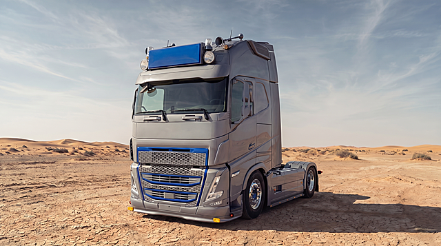 彻底清除车头中网区域残留的Volvo logo痕迹（包括徽标轮廓与凹槽细节），确保中网表面平整干净，保持银灰色车身、蓝色装饰条、荒漠背景及其他所有细节不变，写实高清风格