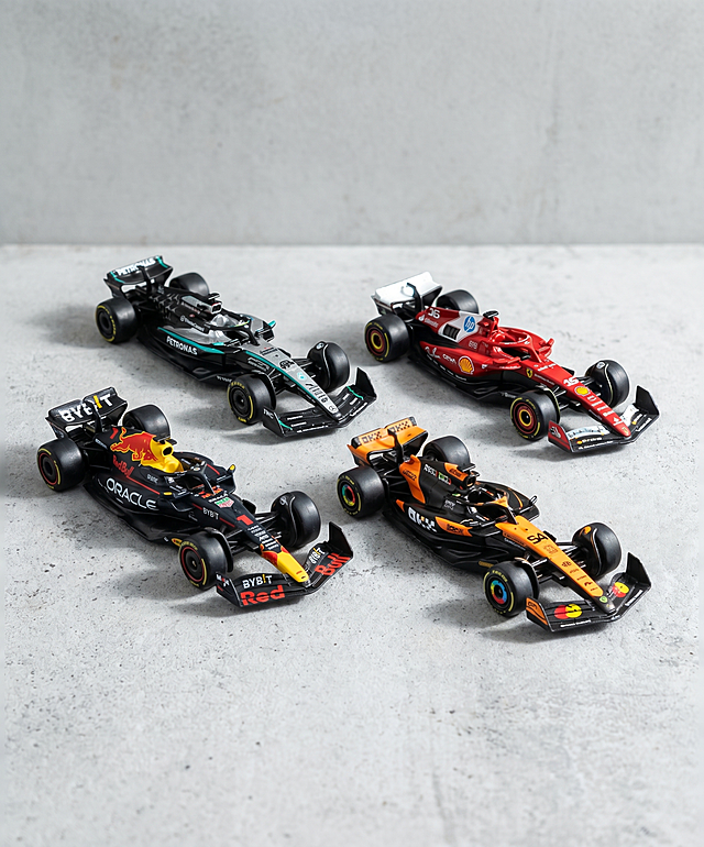 F1赛车模型，严格参照上传产品图，完整保留所有可见组件、部件、轮廓形状、结构、比例、材质质感、颜色与上传图完全一致，严禁扭曲变形和色差。
室内展示空间。
高级灰水泥色调，整体低饱和度，还原参考图的素朴质感。
四辆F1赛车模型组合展示，保持原产品图的排列位置关系。
柔和顶侧漫射自然光（完全复刻参考图的光影方向和质感），产品受光面泛起浅灰高光，暗部及边缘映射深灰色环境阴影光晕，每个模型都有自然的明暗过渡，完全融入环境，杜绝贴片感。
画面中心构图，所有产品完整入画，产品占据画面主体区域。
静态陈列，整体干净简洁。
微俯10°平视视角，和参考图保持一致的拍摄角度。
全量换款：①承载面：参考图浅灰色水泥桌面 → 保持浅灰色水泥材质桌面，微调纹理细节；②背景：参考图浅灰色水泥墙 → 保持浅灰色素水泥背景，微调纹理明暗；③文字：移除全部宣传文案和品牌标语，仅保留模型本身的涂装文字。
消除任何额外的广告文字和logo，只保留产品本身的图案文字。
国内电商主图风格，写实摄影，超高清，对焦清晰锐利，材质真实，整体质感和光影完全参考第二张参考图。
4K 分辨率。严格锁定宽高比为 5:6。
