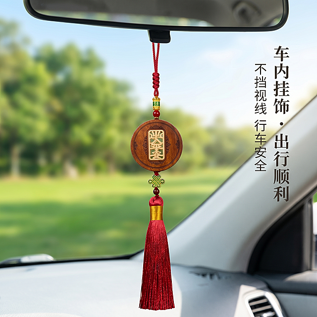 商业级产品摄影
主体：汽车挂件严格参照上传产品图，完整保留所有可见组件、部件、轮廓形状、结构、比例、材质质感、颜色与上传图完全一致，保证中间文字区域保持镂空通透效果，可以透过镂空文字看到对面对的绿色风景，杜绝任何变形、色差、组件缺失、结构偏差。产品占画面约65%，完整不裁切，绝对前景主导，近景构图，产品边缘距画面边缘≥6%，悬挂在汽车后视镜上，承载真实合理。
构图：黄金分割构图，视角平视，偏转10°，产品位于画面视觉焦点。
风格：清新治愈禅意国风。
场景概念：汽车内空间，自然光透过前挡风车窗，挂件悬挂在后视镜上，车窗外是浅绿公园路边和天空，光线可以透过挂件的镂空区域。
空间场景：挂件悬挂于汽车内后视镜处，背景是虚化的车窗外浅绿公园路边树木和浅蓝天空，景深虚化背景突出挂件，车内环境干净简洁，透过挂件的镂空文字区域能清晰看到后面的绿色风景。
文字排版：主标题“车内挂饰・出行顺利”居右，副标题“不挡视线 行车安全”居下，所有文字采用宋体排版，整体右对齐。
配色：主调浅绿和浅蓝60%，辅调浅车内浅灰色25%，点缀挂件深红和木棕色15%，画面颜色：浅绿 / 浅蓝 / 浅灰 / 深红 / 木棕 / 烫金色。
材质：檀木 / 红绳织带 / 金属镶边 / 汽车内饰塑料 / 玻璃车窗，画面实际材质5种：檀木 / 编织绳 / 金属 / 玻璃 / 植被。
光影：自然光从斜前方车窗透入45°，柔和柔光打在挂件主体上，光线穿透镂空区域，产品正面最明亮清晰，阴影边缘柔和过渡，产品边缘有柔和轮廓光切分背景，檀木呈现温润纹理光泽，金属装饰有自然柔和高光。
参数：4K 超清，写实光追，严格锁定宽高比为 1:1。负面提示词：水印、挂件变形、场景违和、背景杂乱、低清、夸张滤镜、多余元素、填实镂空、不透光