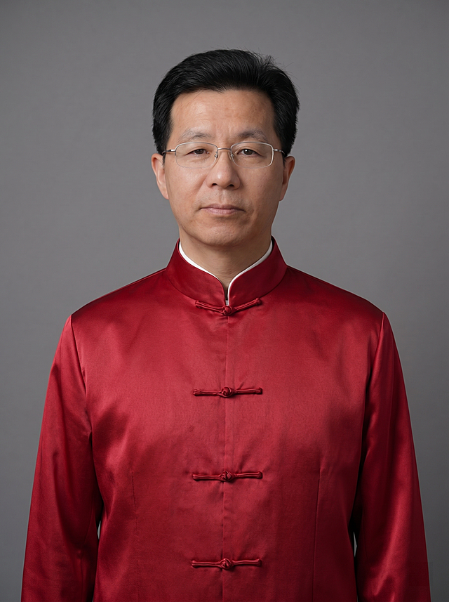 参考图中人物保持原脸型、发型、眼镜与神态，仅将红色中式立领唐装整理得更加整齐服帖：衣领对称挺括、盘扣系紧无松散、衣身无褶皱、下摆平整垂顺；内搭白色打底衣领规整不外露；整体呈现端庄严谨、专业得体的气质。背景为简约中灰色纯色背景，光线均匀柔和，突出人物主体。4K超高清写实摄影风格，面部清晰锐利，肤质自然细腻，正面柔光补光，4800K中性光，面部光比1:1.5，轻透裸肌感，保留真实皮肤细节。严格按照图片内容生成，画面比例3:4。