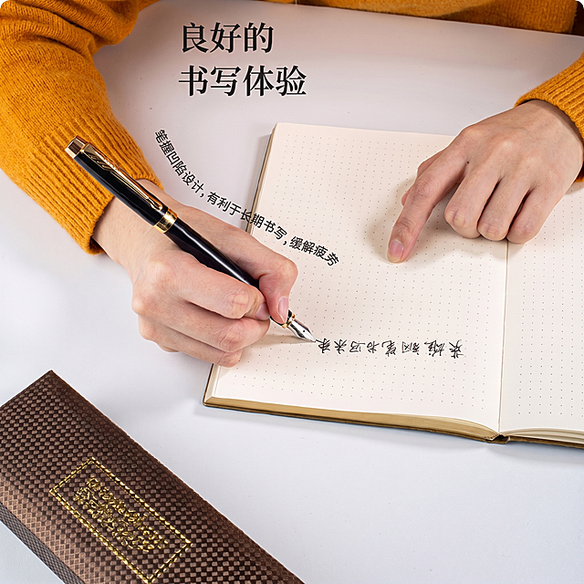 保持原图整体构图、文字内容和姿势不变，将图中手里原有的钢笔替换为图二的纯黑丽雅金钢笔，保留该钢笔原有的黑色笔身、金色装饰和银色笔尖的样式色彩，保持整体光影自然协调