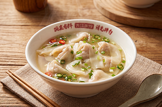 优化图片，保留原有内容，将这碗抄手改造为温馨诱人的美食风格：放在木质桌面上，搭配餐垫餐具，暖色调光线，写实高清，突出食物质感，保留碗上的文字