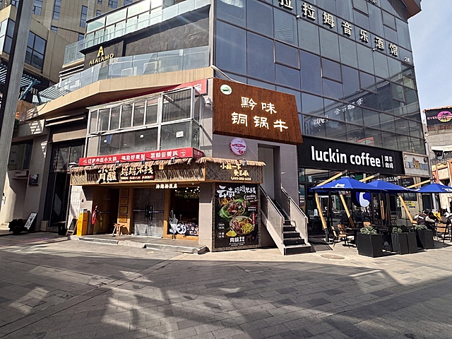 修改右侧墙面门头，将原竖直门头改成平面斜坡门头，保持位置不变；文字“黔味铜锅牛”做成发光字效果，门头底板换成和原图一样木纹纹理的棕色PU板，保留建筑和其他店铺原本内容