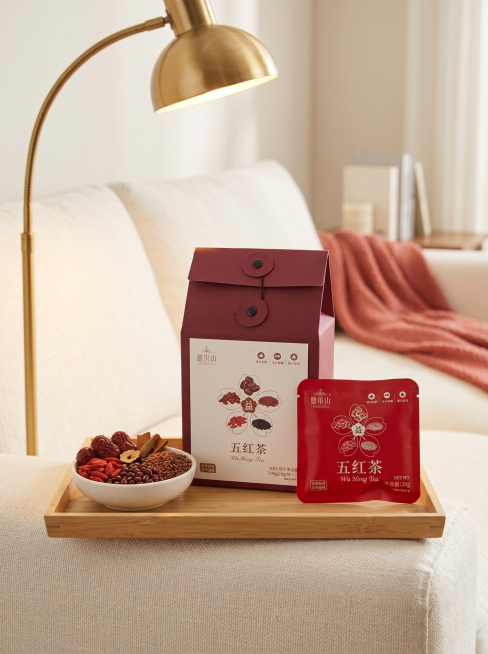 客厅沙发休闲场景，五红茶礼盒和独立茶包组合展示，严格参照上传产品图，完整保留所有可见组件、轮廓、结构、比例、材质、颜色与产品本体上的文字信息，与上传图完全一致。礼盒放在浅木色托盘上，托盘放在米白色沙发预览效果