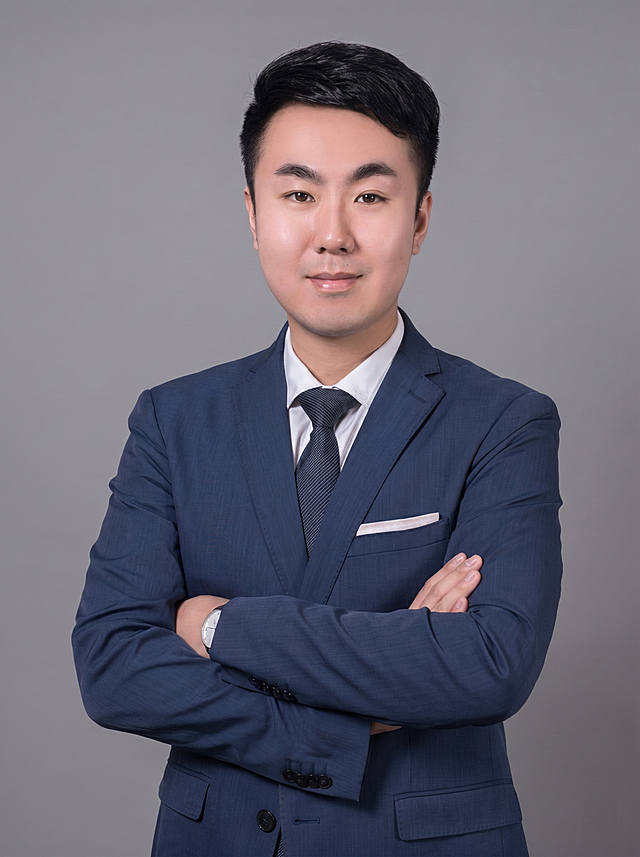参考图中保留人物脸型、发型、年龄等特征生成企业管理层商务半身形象照,标准焦段50mm,f/4光圈(f/2.8-f/4区间),平视视角(镜头与人物视线齐平);人物占画面70%,人物居中(居中构图),位于画面中心,为视觉聚焦点,入境范围头部及以下至臀部下方10cm(半身像);左右留少量背景空间;头部与画面顶部保留5%空间;头部发型完整,头肩比例协调,人物结构准确;身穿深蓝色精纺羊毛混纺西装外套,(平驳领设计,面料呈细腻微微哑光质感);内搭白色高支棉衬衫;下装深蓝色精纺羊毛混纺西裤;着装正式干练;权威沉稳、从容果决、值得信赖;身形匀称,姿态端正,身体挺拔。呈站姿双手抱胸,肢体放松且自信;发梢微微修整,干练大气,发质微微柔顺，微微蓬松。佩戴精致手表配饰。主体锐利,背景光线均匀柔和,强化色彩对比的高级感。简约微微中度灰色纯色背景(呈现均匀柔和质感),极简干净;画质超高分辨率、细节清晰,现代精致感风格;肤质精细化处理;眼神直视镜头,目光坚定且澄澈,表情自然。嘴角上扬;肤质自然细腻,肤色健康均匀,皮肤状态清爽干净,保留真实皮肤细节｡正面柔光补光,4800K中性光,面部光比1:1.5｡中近景写实摄影,对焦清晰,面部雾面柔光,轻透裸肌感,高清保留皮肤细节｡分辨率4K,去除人物之外的所有元素。严格按照图片内容生成。画面比例3:4