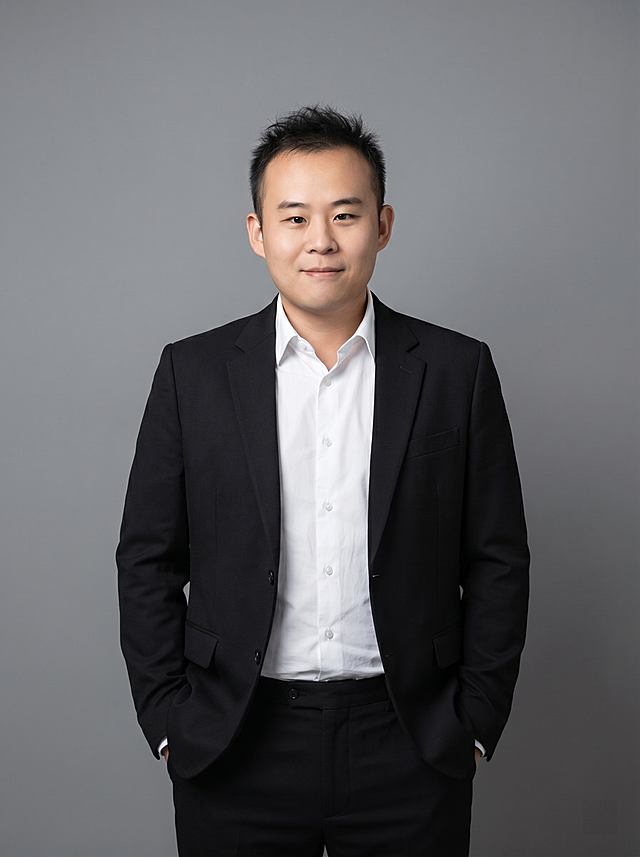 参考图中保留人物脸型、发型、年龄等特征生成设计师职场形象照，标准焦段50mm，f/4光圈，平视视角，镜头与人物视线齐平；人物占画面70%，人物居中，位于画面中心，为视觉聚焦点，入境范围头部及以下至臀部下方10cm(半身像)；左右留少量背景空间；头部与画面顶部保留5%空间；头部发型完整，头肩比例协调，人物结构准确；发质微微柔顺，微微蓬松；身穿设计师款小众黑色精纺羊毛混纺西装外套，解构剪裁，面料呈细腻微微哑光质感；内搭白色高支精梳棉衬衫；下装同料黑色精纺羊毛混纺西裤；着装正式干练，前卫自信，灵感充沛，艺术格调，张扬有态度；身形匀称，姿态端正，身体挺拔，呈站姿双手插兜的自然姿态，肢体放松且自信；简约微微中度灰色纯色背景，呈现均匀柔和质感，背景光线均匀柔和，强化色彩对比的高级感，极简干净；画质超高分辨率、细节清晰，现代精致感风格；肤质精细化处理；眼神直视镜头，目光坚定且澄澈，表情自然，嘴角上扬；肤质自然细腻，肤色健康均匀，皮肤状态清爽干净，保留真实皮肤细节｡正面柔光补光，4800K中性光，面部光比1:1.5｡中近景写实摄影，对焦清晰，面部雾面柔光，轻透裸肌感，高清保留皮肤细节；分辨率4K，去除人物之外的所有元素，严格按照图片内容生成，画面比例3:4