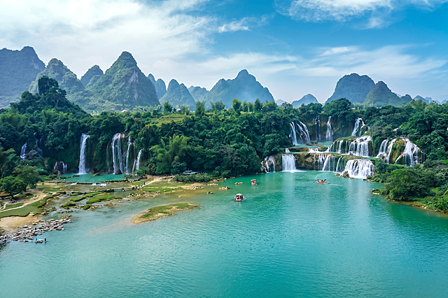 修改图片，将前景的芭蕉林替换为清澈碧绿的湖面，湖面延续原有河道水域的颜色和质感，和原有河水自然衔接，整体景色风格统一，保持瀑布群和背景山峰不变，画面自然和谐