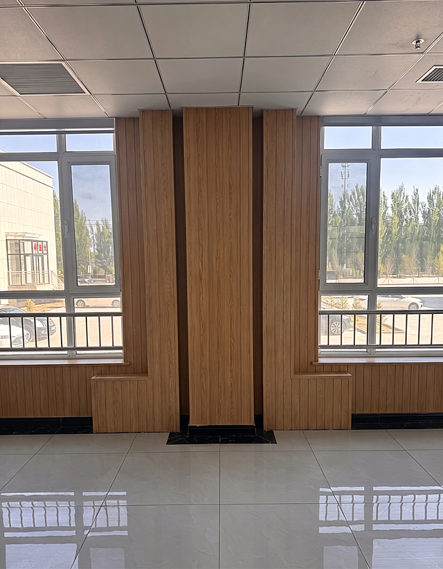 将图中所有裸露的金属管道都用和墙体一致的浅棕色木纹墙板包裹起来，保持房间整体风格和其他结构不变，自然真实