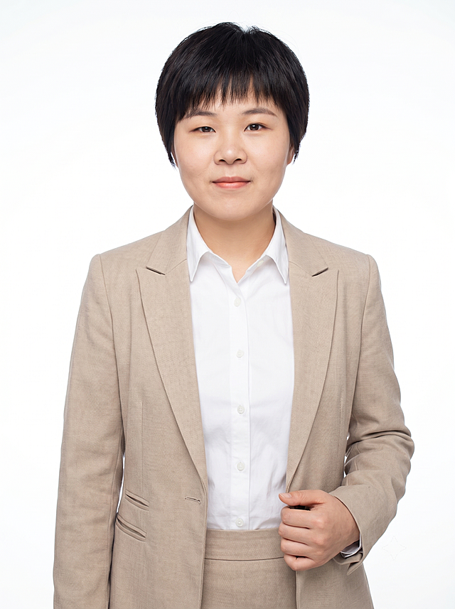 参考图中保留人物脸型、发型、年龄等特征生成职场形象照,标准焦段50mm,f/4光圈(f/2.8-f/4区间),平视视角(镜头与人物视线齐平);人物占画面70%,人物居中(居中构图),位于画面中心,为视觉聚焦点,入境范围头部及以下至臀部下方10cm(半身像);左右留少量背景空间;头部与画面顶部保留5%空间;头部发型完整,头肩比例协调,人物结构准确;发质微微柔顺，微微蓬松。身穿浅米色精纺羊毛混纺西装外套,(平驳领设计,面料呈细腻微微哑光质感);内搭白色高支精梳棉衬衫;下装浅米色精纺羊毛混纺西装套裙;着装正式干练;专业稳重;身形匀称,姿态端正,身体挺拔。呈自然站姿，右手轻握西装前襟，肢体放松且自信;主体锐利;纯色纯白背景，自然过渡，呈现均匀柔和质感,背景光线均匀柔和,强化色彩对比的高级感,极简干净;画质超高分辨率、细节清晰,现代精致感风格;肤质精细化处理;眼神直视镜头,目光坚定且澄澈,表情自然。嘴角上扬;清透自然裸妆(轻薄底妆+淡唇妆)妆感轻薄轻透裸肌感,通透感肤质,肤质自然细腻,肤色健康均匀,雾面柔光裸肌感,保留真实皮肤细节｡正面柔光补光,4800K中性光,面部光比1:1.5,色调明亮｡中近景写实摄影,对焦清晰,高清保留皮肤细节。分辨率4K,去除人物之外的所有元素。严格按照图片内容生成。画面比例3:4