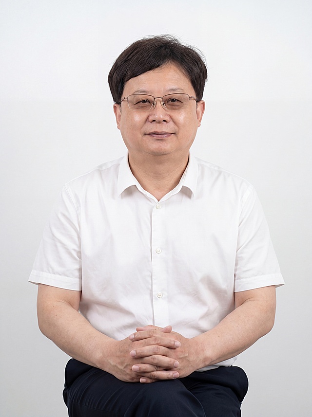 参考图中保留人物脸型、发型、年龄等特征生成职场形象照,标准焦段50mm,f/4光圈(f/2.8-f/4区间),平视视角(镜头与人物视线齐平);人物占画面70%,人物居中(居中构图),位于画面中心,为视觉聚焦点,入境范围头部及以下至臀部下方10cm(半身像);左右留少量背景空间;头部与画面顶部保留5%空间;头部发型完整,头肩比例协调,人物结构准确;发质微微柔顺，微微蓬松。身穿白色高支棉短袖衬衫,(挺括剪裁,面料透气细腻);下装深色西裤;着装正式干练;沉稳可靠、公正亲和;身形匀称,姿态端正,身体挺拔。呈坐姿，双手交叠放在桌上，肢体放松且自信;保留眼镜配饰;简约纯白色纯色背景(呈现均匀柔和质感),背景光线均匀柔和,强化色彩对比的高级感。极简干净;画质超高分辨率、细节清晰,现代精致感风格;肤质精细化处理;眼神直视镜头,目光坚定且澄澈,表情自然。嘴角上扬;肤质自然细腻,肤色健康均匀,皮肤状态清爽干净,保留真实皮肤细节｡正面柔光补光,4800K中性光,面部光比1:1.5｡中近景写实摄影,对焦清晰,面部雾面柔光,轻透裸肌感,高清保留皮肤细节;分辨率4K,去除人物之外原背景和桌子，去除所有多余配饰，只保留眼镜。严格按照图片内容生成。画面比例3:4