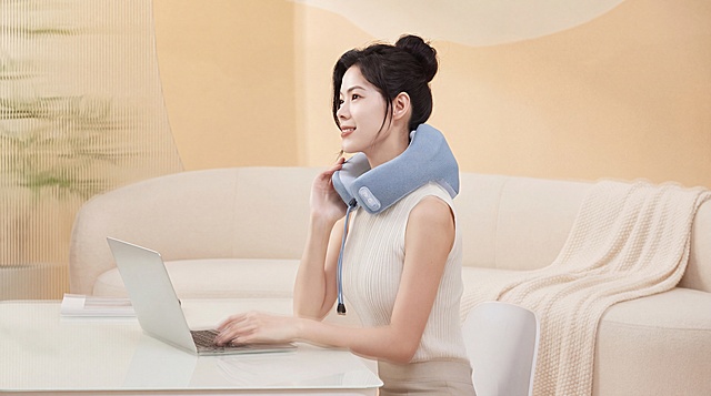 U型颈椎按摩枕，严格参照上传产品图https://gdesign-dam-hz.dancf.com/36599092395754655/e1068be6ce0549a08c6c0fb290d18803.png，完整保留所有可见组件、部件、轮廓形状、结构、比例、材质质感、颜色与产品本体上的文字信息，与上传图完全一致；保持人物姿态和产品位置不变，生成类似图1https://0.jpg的浅暖杏家居场景，保留图1的浅暖米杏色调、室内温馨家居氛围、柔和侧前自然光；产品受光面泛起浅暖杏色、暗部映射米白光晕，与环境物理融合；消除产品外原有文字；4K 分辨率，严格锁定宽高比为 16:9。