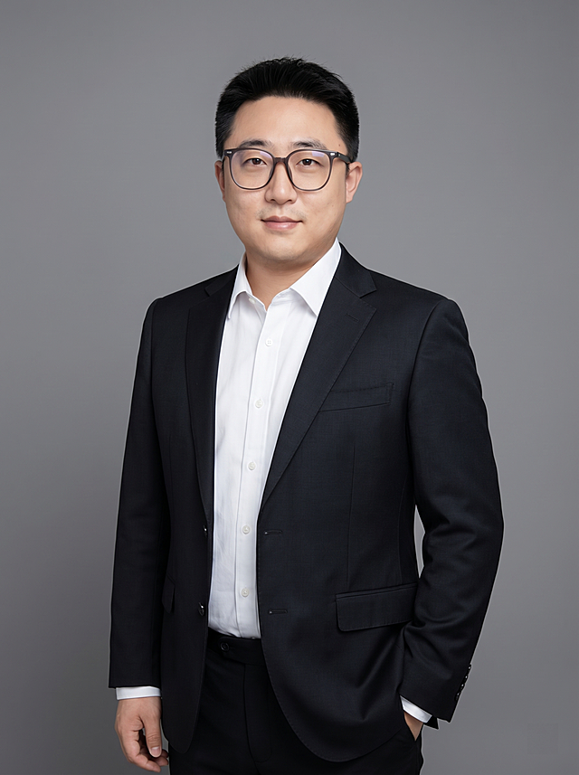 参考图中保留人物脸型、发型、年龄等特征生成职场形象照,标准焦段50mm,f/4光圈(f/2.8-f/4区间),平视视角(镜头与人物视线齐平);人物占画面70%,人物居中(居中构图),位于画面中心,为视觉聚焦点,入境范围头部及以下至臀部下方10cm(半身像);左右留少量背景空间;头部与画面顶部保留5%空间;头部发型完整,头肩比例协调,人物结构准确;发质微微柔顺，微微蓬松。身穿深黑色精纺羊毛混纺西装外套,(平驳领设计,面料呈细腻微微哑光质感);内搭白色高支精梳棉衬衫;下装深黑色精纺羊毛混纺西裤;着装正式干练;专业稳重;瘦身塑形，身形匀称,姿态端正,身体挺拔。呈单手插兜的自然姿态，肢体放松且自信;佩戴黑框眼镜;简约微微中度灰色纯色背景(呈现均匀柔和质感),背景光线均匀柔和,强化色彩对比的高级感。极简干净;画质超高分辨率、细节清晰,现代精致感风格;肤质精细化处理;眼神直视镜头,目光坚定且澄澈,表情自然。嘴角上扬;肤质自然细腻,肤色健康均匀,皮肤状态清爽干净,保留真实皮肤细节｡正面柔光补光,4800K中性光,面部光比1:1.5｡中近景写实摄影,对焦清晰,面部雾面柔光,轻透裸肌感,高清保留皮肤细节｡分辨率4K,去除人物之外的所有元素。严格按照图片内容生成。画面比例3:4