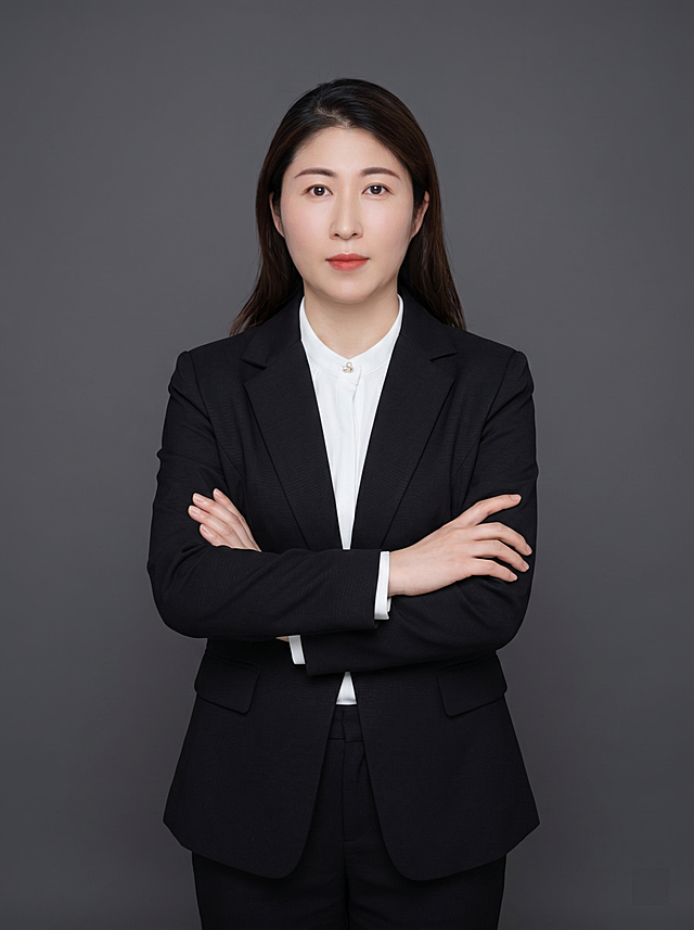参考图中保留人物脸型、发型、年龄等特征生成职场形象照,标准焦段50mm,f/4光圈(f/2.8-f/4区间),平视视角(镜头与人物视线齐平);人物占画面70%,人物居中(居中构图),位于画面中心,为视觉聚焦点,入境范围头部及以下至臀部下方10cm(半身像);左右留少量背景空间;头部与画面顶部保留5%空间;头部发型完整,头肩比例协调,人物结构准确;身穿黑色亚面精纺面料西装外套,(平驳领设计,面料呈细腻微微哑光质感);内搭白色衬衫;下装黑色亚面精纺面料西裤;着装正式干练;专业稳重,身形匀称,姿态端正,身体挺拔。呈正面抱胸的自然站立姿态:左臂搭于右臂上方,肩颈自然松弛下沉,姿态自信从容;发梢微微修整,干练大气,主体锐利,背景光线均匀柔和,强化色彩对比的高级感。简约冷调深灰色纯色背景(呈现均匀柔和质感),极简干净;画质超高分辨率、细节清晰,现代精致感风格;肤质精细化处理;眼神直视镜头,目光坚定且澄澈,表情自然。肤质自然细腻,肤色健康均匀,哑光肤质清爽干净,保留真实皮肤细节;杰作,最佳画质,超高细节,写实摄影,中近景人像,皮肤质感自然清晰,柔光,正面补光,画面干净清新,高清皮肤细节;面部光比1:1.5,4800K中性光,微微修饰脸型,肤质哑光细腻,面部雾面柔光,轻透裸肌感,真实毛孔纹理;分辨率4K,严格按照图片内容生成,画面比例3:4