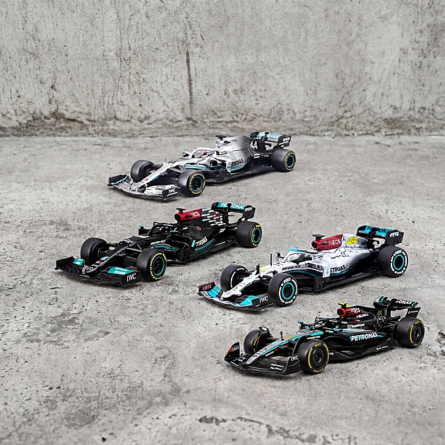 F1赛车模型，严格参照上传产品图（image1），完整保留所有可见组件、部件、轮廓形状、结构、比例、材质质感、颜色与产品本体上的文字信息，与上传图完全一致。
室外水泥地面场景，自然灰调工业风色调。
保留参考图（image2）骨架：承载面为水泥地面、背景为水泥墙面，整体排布方式与光影氛围一致。侧前方自然光，产品受光面泛起水泥灰色、暗部映射浅灰光晕，与环境物理融合。
产品居中展示，保持所有四辆赛车组合排布，微俯视角相对参考图偏转30度。
全量换款清单：
①背景墙面：参考图浅灰色水泥墙 → 生成图浅灰色复古水泥墙，同水泥材质换纹理色调
②地面：参考图浅灰色水泥地 → 生成图浅灰色粗糙水泥地，同水泥材质换纹理
③其他赛车：参考图其他车队赛车 → 保留数量和位置，仅为同材质换不同车队款式，保持赛车品类
相似度50%，保留图1商品外观颜色不变，实物拍摄展示，消除品牌文字之外的多余信息。
4K 分辨率，严格锁定宽高比为 1:1