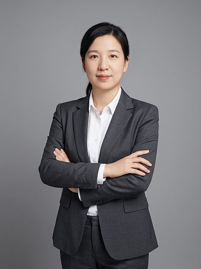 参考图中保留人物脸型、发型、年龄等特征生成职场形象照,标准焦段50mm,f/4光圈(f/2.8-f/4区间),平视视角(镜头与人物视线齐平);人物占画面70%,人物居中(居中构图),位于画面中心,为视觉聚焦点,入境范围头部及以下至臀部下方10cm(半身像);左右留少量背景空间;头部与画面顶部保留5%空间;头部发型完整,头肩比例协调,人物结构准确;发质微微柔顺，微微蓬松。身穿深灰色精纺羊毛混纺西装外套,(平驳领设计,面料呈细腻微微哑光质感);内搭白色高支精梳棉衬衫;下装深灰色精纺羊毛混纺西裤;着装正式干练;专业稳重;身形匀称,姿态端正,身体挺拔。呈站姿双手抱胸，肢体放松且自信;佩戴精致配饰;简约微微中度灰色纯色背景(呈现均匀柔和质感),背景光线均匀柔和,强化色彩对比的高级感。极简干净;画质超高分辨率、细节清晰,现代精致感风格;肤质精细化处理;眼神直视镜头,目光坚定且澄澈,表情自然。嘴角上扬;分辨率4K,去除人物之外的所有元素。严格按照图片内容生成。画面比例3:4