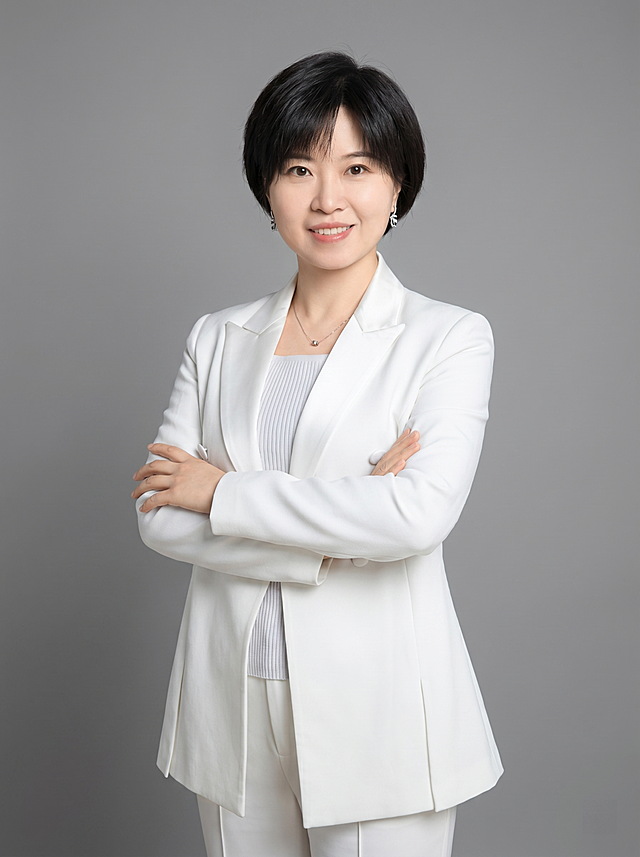 参考图中保留人物脸型、发型、年龄等特征生成通用知识课程讲师形象照，标准焦段50mm，f/4光圈，平视视角，镜头与人物视线齐平；人物占画面70%，人物居中，居中构图，位于画面中心，为视觉聚焦点，入境范围头部及以下至臀部下方10cm，半身像；左右留少量背景空间；头部与画面顶部保留5%空间；头部发型完整，头肩比例协调，人物结构准确；发质微微柔顺，微微蓬松。身穿白色精纺羊毛混纺西装外套，平驳领设计，面料呈细腻微微哑光质感；内搭浅灰色条纹针织内搭；下装白色精纺羊毛混纺西装裤；着装正式干练；专业亲和，身形匀称，姿态端正，身体挺拔。呈站姿双手抱胸的自然姿态，肢体放松且自信；佩戴精致配饰；简约微微中度灰色纯色背景，呈现均匀柔和质感，背景光线均匀柔和，强化色彩对比的高级感，极简干净；画质超高分辨率、细节清晰，现代精致感风格；肤质精细化处理；眼神直视镜头，目光坚定且澄澈，表情自然，嘴角上扬；清透自然裸妆，轻薄底妆+淡唇妆，妆感轻薄轻透裸肌感，通透感肤质，肤质自然细腻，肤色健康均匀，雾面柔光裸肌感，保留真实皮肤细节｡正面柔光补光，4800K中性光，面部光比1:1.5，色调明亮｡中近景写实摄影，对焦清晰，高清保留皮肤细节；分辨率4K，去除人物之外的所有元素。严格按照图片内容生成，画面比例3:4