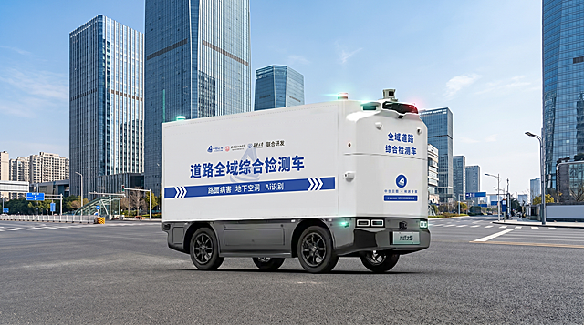 商业级产品摄影，无人道路全域综合检测车正在城市道路进行检测作业，完整保留车辆所有文字logo和外观细节，横版构图，背景为现代化城市开阔主干道场景，白天晴朗蓝天，干净科技风，产品作为视觉主体，4K超高清写实，严格锁定宽高比16:9