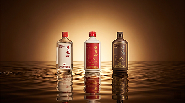 三瓶不同款式白酒整体合影，严格参照提取的产品图，完整保留所有可见组件、部件、轮廓形状、结构、比例、材质质感、颜色与产品本体上的文字信息（logo / 型号 / 规格 / 参数），与上传图完全一致。棚拍静物场景，暖棕深咖色调，产品放置在水面承载面上，保持参考图光影氛围：主光从产品正前方均匀漫射，产品受光面泛起暖棕金色，暗部与边缘映射深棕阴影光晕，与环境物理融合自然。三瓶横向并排居中放置，中景构图，水面有自然波纹动态感，相对参考图视角微正。全量换款清单：①背景：参考图渐变深棕到浅黄背景→生成渐变深棕到暖金暗调背景，保持渐变光晕和柔和中心打光效果；②承载面：参考图水面波纹→保持水面波纹承载面，同材质调整波纹细节。整体保持图一的场景光影和氛围不变，产品颜色和质感保持原貌不变，保证接触阴影与柔和反光，整体融合自然，效果如真实拍摄。严格锁定宽高比为 16:9。