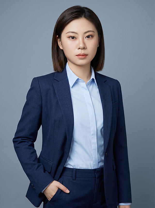 参考图片中人物特征生成通用职场形象照，保留人物脸型和基础特征，身穿藏蓝色精纺羊毛混纺西装外套，内搭浅蓝色高支精梳棉衬衫，下装同材质藏蓝色西裤，着装正式干练，专业沉稳，身形匀称，姿态端正，身体挺拔，呈自然站姿，单手插兜，肢体放松且自信，去除原配饰，发梢修整干练大气，背景为冷灰蓝色纯色背景，光线均匀柔和，极简干净，画质超高分辨率细节清晰，现代精致风格，肤质精细化处理，眼神直视镜头，目光坚定澄澈，表情自然，肤色均匀，哑光清爽干净，保留真实皮肤细节，杰作，最佳画质，超高细节，写实摄影，中近景人像，皮肤质感自然清晰，柔光正面补光，高清皮肤细节，面部光比合适，微微修饰脸型，真实毛孔纹理，分辨率4K，画面比例3:4