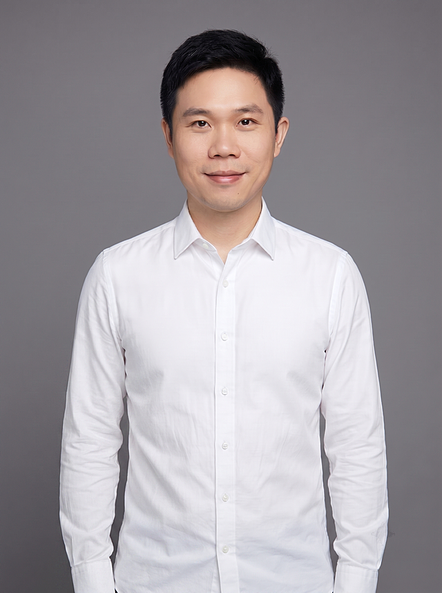 参考图中保留人物脸型、发型、年龄等特征生成职场形象照,标准焦段50mm,f/4光圈(f/2.8-f/4区间),平视视角(镜头与人物视线齐平);人物占画面70%,人物居中(居中构图),位于画面中心,为视觉聚焦点,入境范围头部及以下至臀部下方10cm(半身像);左右留少量背景空间;头部与画面顶部保留5%空间;头部发型完整,头肩比例协调,人物结构准确;发质微微柔顺，微微蓬松。身穿高支精梳棉白色衬衫;着装正式干练;专业稳重;身形匀称,姿态端正,身体挺拔。呈站姿，双手自然垂直下垂贴于身体两侧，肢体放松且自信;去除手表配饰;简约微微中度灰色纯色背景(呈现均匀柔和质感),背景光线均匀柔和,强化色彩对比的高级感。极简干净;画质超高分辨率、细节清晰,现代精致感风格;肤质精细化处理;眼神直视镜头,目光坚定且澄澈,表情自然。嘴角上扬;肤质自然细腻,肤色健康均匀,皮肤状态清爽干净,保留真实皮肤细节｡正面柔光补光,4800K中性光,面部光比1:1.5｡中近景写实摄影,对焦清晰,面部雾面柔光,轻透裸肌感,高清保留皮肤细节｡分辨率4K,去除人物之外的所有元素。严格按照图片内容生成。画面比例3:4