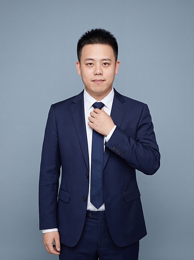 参考图中保留人物脸型、发型、年龄等特征生成职场形象照，标准焦段50mm，f/4光圈，平视视角（镜头与人物视线齐平）；人物占画面70%，人物居中，位于画面中心，为视觉聚焦点，入境范围头部及以下至臀部下方10cm（半身像）；左右留少量背景空间；头部与画面顶部保留5%空间；头部发型完整，头肩比例协调，人物结构准确；发质微微柔顺，微微蓬松。身穿藏青色精纺羊毛混纺西装外套，平驳领设计，面料呈细腻微微哑光质感；内搭白色高支棉衬衫；下装藏青色精纺羊毛混纺直筒西装裤；搭配低调素色领带；着装正式干练；严谨理性、不怒自威；身形匀称，姿态端正，身体挺拔。呈站姿手扶领带的自然姿态，肢体放松且自信。简约冷灰蓝纯色背景，呈现均匀柔和质感，背景光线均匀柔和，强化色彩对比的高级感，极简干净。画质超高分辨率、细节清晰，现代精致感风格；肤质精细化处理；眼神直视镜头，目光坚定且澄澈，表情自然。嘴角上扬；肤质自然细腻，肤色健康均匀，皮肤状态清爽干净，保留真实皮肤细节。正面柔光补光，4800K中性光，面部光比1:1.5。中近景写实摄影，对焦清晰，面部雾面柔光，轻透裸肌感，高清保留皮肤细节。分辨率4K，去除人物之外的所有元素，严格按照图片内容生成，画面比例3:4
