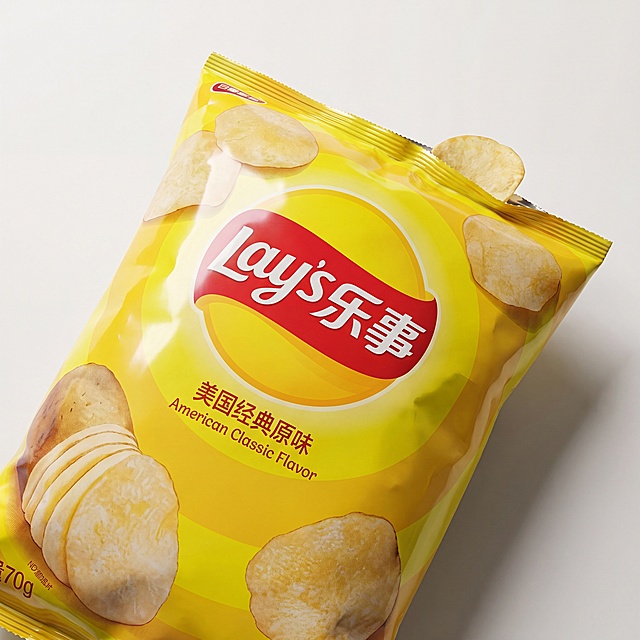 1:1 正方形微距产品特写，包装印刷工艺细节图，严格还原上传的产品图，包括包装设计、颜色、LOGO 位置、文字内容、图案元素等所有细节，产品外观必须与参考图完全一致，不得改变包装设计、配色方案或品牌元素，保持产品的真实材质质感（高光复合塑料包装袋）。主体聚焦乐事原味薯片包装袋正面核心区域，红色飘带 Lay's 品牌 LOGO、“美国经典原味” 中英文文字、马铃薯切片印刷图案、侧边 70g 净含量小字 1:1 原样复刻原图，袋口轻微开口，一小片薯片卡在封口位置。单侧柔光箱定向打光，柔和漫射光源在亮黄色塑料包装表层形成细腻渐变高光，微距 f2.4 大光圈镜头，8K 超高清锐化画质，极致清晰展现油墨印刷网点肌理、包装袋封口压边纹路、塑料薄膜细微拉丝纹理。背景选用纯净哑光米白卡纸，轻微虚化处理，无多余杂物干扰主体视线。整体画面重心落在品牌标识与产品印刷信息上，用于展示正品包装细节、品牌标识工艺，配色沿用产品原生黄红配色不做调色改动，商业产品写实特写，适配详情包装正品细节说明板块，无卡通、手绘、滤镜变形。负面词：LOGO 扭曲变形、文字缺漏、图案篡改、包装换色、手绘质感、卡通滤镜、边缘糊化、画面水印、多余印花、高光过曝发白、暗部死黑、破损裂口包装、霉变痕迹、多余散落薯块、异形边角、色彩偏移、噪点密集、额外广告语、贴图拼接、杂乱光斑、印刷错位、额外花纹、磨砂质感（原包装高光）、畸形油墨、色块晕染、多余装饰图案
