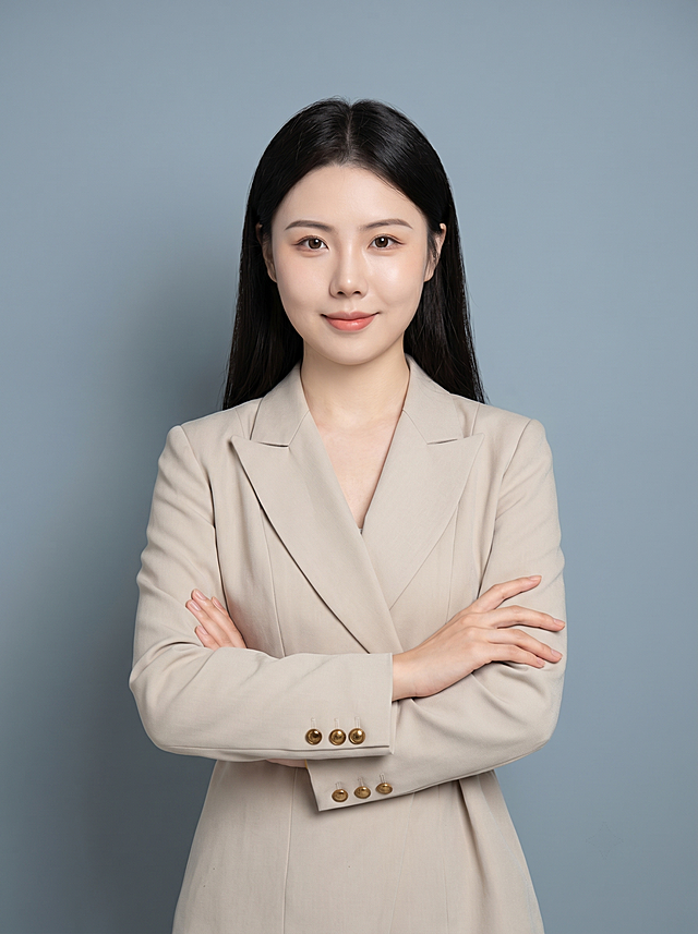参考图片1的肖像姿势、服装、构图和比例，保留图片2中人物的面部特征和发型，为图片2人物生成教师/公职人员形象照，参考图中保留人物脸型、发型、年龄等特征生成职场形象照,标准焦段50mm,f/4光圈(f/2.8-f/4区间),平视视角(镜头与人物视线齐平);人物占画面70%,人物居中(居中构图),位于画面中心,为视觉聚焦点,入境范围头部及以下至臀部下方10cm(半身像);左右留少量背景空间;头部与画面顶部保留5%空间;头部发型完整,头肩比例协调,人物结构准确;身穿奶茶色精纺羊毛混纺西装外套，平驳领设计，面料呈细腻微微哑光质感；下装奶茶色精纺羊毛混纺西装套裙；着装正式干练;端庄知性;身形匀称,姿态端正,身体挺拔。呈双手抱胸的自然姿态，肢体放松且自信;发质微微柔顺，微微蓬松。简约冷灰蓝灰色纯色背景，呈现均匀柔和质感，背景光线均匀柔和，强化色彩对比的高级感，极简干净;画质超高分辨率、细节清晰，现代精致感风格;肤质精细化处理;眼神直视镜头，目光坚定且澄澈，表情自然。嘴角上扬;清透自然裸妆，轻薄底妆+淡唇妆，妆感轻薄轻透裸肌感，通透感肤质，肤质自然细腻，肤色健康均匀，雾面柔光裸肌感，保留真实皮肤细节｡正面柔光补光，4800K中性光，面部光比1:1.5，色调明亮｡中近景写实摄影，对焦清晰，高清保留皮肤细节｡分辨率4K，去除人物之外的所有元素。严格按照图片内容生成。画面比例3:4