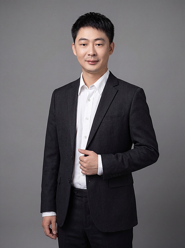 参考图中保留人物脸型、发型、年龄等特征生成职场形象照,标准焦段50mm,f/4光圈(f/2.8-f/4区间),平视视角(镜头与人物视线齐平);人物占画面70%,人物居中(居中构图),位于画面中心,为视觉聚焦点,入境范围头部及以下至臀部下方10cm(半身像);左右留少量背景空间;头部与画面顶部保留5%空间;头部发型完整,头肩比例协调,人物结构准确;发质微微柔顺，微微蓬松。身穿深黑色精纺羊毛混纺西装外套,(平驳领设计,面料呈细腻微微哑光质感);内搭白色高支精梳棉衬衫;下装深黑色精纺羊毛混纺西裤;着装正式干练;专业稳重;身形匀称,姿态端正,身体挺拔。呈自然站姿，右手轻握西装前襟，肢体放松且自信;简约微微中度灰色纯色背景(呈现均匀柔和质感),背景光线均匀柔和,强化色彩对比的高级感。极简干净;画质超高分辨率、细节清晰,现代精致感风格;肤质精细化处理;眼神直视镜头,目光坚定且澄澈,表情自然。嘴角上扬;肤质自然细腻,肤色健康均匀,皮肤状态清爽干净,保留真实皮肤细节｡正面柔光补光,4800K中性光,面部光比1:1.5｡中近景写实摄影,对焦清晰,面部雾面柔光,轻透裸肌感,高清保留皮肤细节｡分辨率4K,去除人物之外的所有元素。严格按照图片内容生成。画面比例3:4