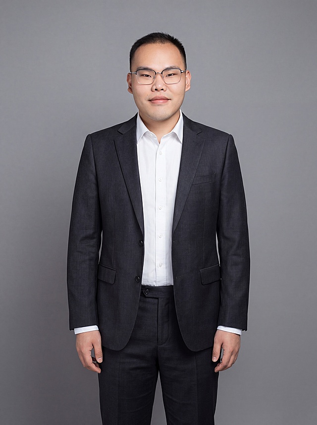 参考图中保留人物脸型、发型、年龄等特征生成通用职场正装全身形象照，标准焦段50mm，f/4光圈，平视视角，镜头与人物视线齐平；人物占画面，人物居中构图，位于画面中心，为视觉聚焦点，全身照，展现人物完整身形；头部与画面顶部保留合理空间，头部发型完整，头身比例协调，人物结构准确；身穿深黑色精纺羊毛混纺西装外套，平驳领设计，面料呈细腻微微哑光质感；内搭白色高支精梳棉衬衫；下装深黑色精纺羊毛混纺西裤；着装正式干练；专业稳重；身形匀称，姿态端正，身体挺拔。呈自然站姿，双手自然下垂，肢体放松且自信；佩戴原有方框眼镜；发质微微柔顺，微微蓬松；简约微微中度灰色纯色背景(呈现均匀柔和质感)，背景光线均匀柔和，强化色彩对比的高级感，极简干净；画质超高分辨率、细节清晰，现代精致感风格；肤质精细化处理；眼神直视镜头，目光坚定且澄澈，表情自然。嘴角上扬；肤质自然细腻，肤色健康均匀，皮肤状态清爽干净，保留真实皮肤细节｡正面柔光补光，4800K中性光，面部光比1:1.5｡中近景写实摄影，对焦清晰，面部雾面柔光，轻透裸肌感，高清保留皮肤细节；分辨率4K，去除人物之外的所有元素；严格按照图片内容生成；画面比例3:4