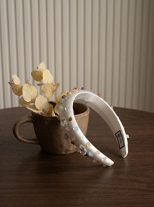 发箍，严格参照上传产品图https://gdesign-dam-hz.dancf.com/36609662893413487/9b7d6d373a244d59a9297a97c6fbd24f.png，完整保留所有可见组件、部件、轮廓形状、结构、比例、材质质感、颜色与上传图完全一致。
室内家居咖啡角桌面，参考图https://1.jpg简约ins风，保留场景骨架，相似度50%，低饱和浅灰暖色调。
发箍搭配复古陶瓷咖啡杯装饰，侧前方柔和漫射光（还原参考图自然光方向），产品受光面泛起暖棕浅调、暗部映射深灰光晕，与环境物理融合。中景偏左微俯25°视角，静态摆放。
全量换款清单：①花瓶：参考图米白异形粗陶 → 生成图奶咖粗陶咖啡杯；②干枝：参考图棕色干枝枯叶 → 生成图浅黄尤加利干叶；③背景墙面：参考图纯白墙面 → 生成图米白竖纹乳胶漆墙面；④桌面：参考图深棕实木桌面 → 生成图胡桃木深棕桌面。
消除品牌文字，保留产品本体logo。
4K分辨率，严格锁定宽高比为 3:4。