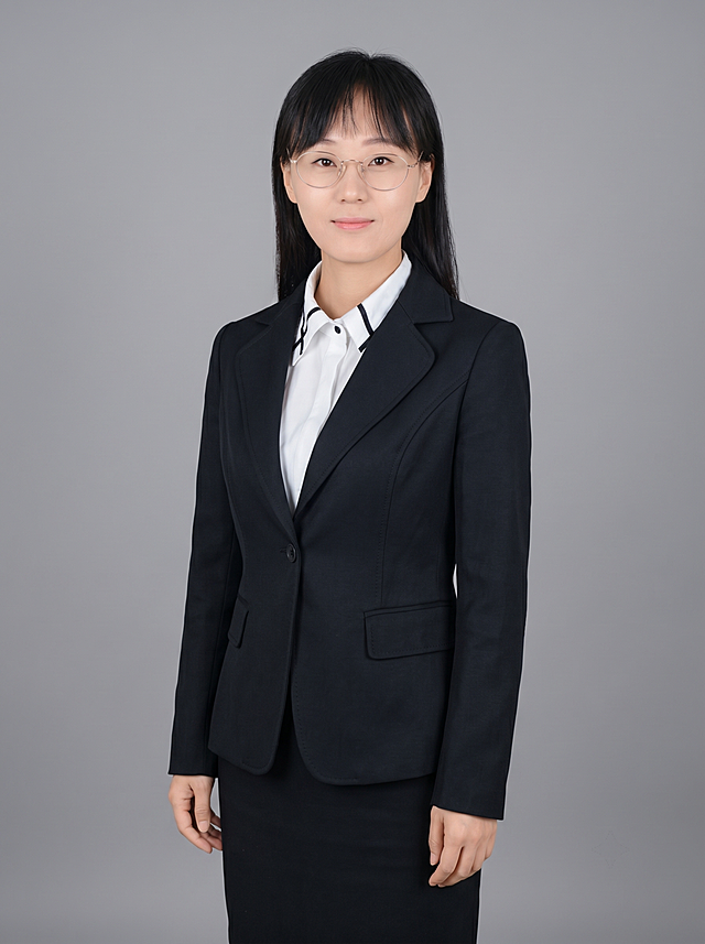 参考图中保留人物脸型、发型、年龄等特征生成职场全身形象照，标准焦段50mm,f/4光圈，平视视角，镜头与人物视线齐平；人物占画面，人物居中，居中构图，位于画面中心，为视觉聚焦点，全身照，展现人物完整身形；左右留少量背景空间；头部与画面顶部保留5%空间；头部发型完整，头肩比例协调，人物结构准确；身穿深黑色精纺羊毛混纺西装外套，平驳领设计，面料呈细腻微微哑光质感；内搭白色高支精梳棉衬衫；下装深黑色精纺羊毛混纺西装套裙；着装正式干练；专业稳重；身形匀称，姿态端正，身体挺拔。呈自然站姿，双臂自然下垂，肢体放松且自信；发质微微柔顺，微微蓬松。佩戴眼镜；简约中性灰色纯色背景，呈现均匀柔和质感，背景光线均匀柔和，强化色彩对比的高级感，极简干净；画质超高分辨率、细节清晰，现代精致感风格；肤质精细化处理；眼神直视镜头，目光坚定且澄澈，表情自然。嘴角上扬；清透自然裸妆，轻薄底妆+淡唇妆，妆感轻薄轻透裸肌感，通透感肤质，肤质自然细腻，肤色健康均匀，雾面柔光裸肌感，保留真实皮肤细节｡正面柔光补光，4800K中性光，面部光比1:1.5，色调明亮｡中近景写实摄影，对焦清晰，高清保留皮肤细节；分辨率4K，去除人物之外的所有元素。严格按照图片内容生成。画面比例3:4