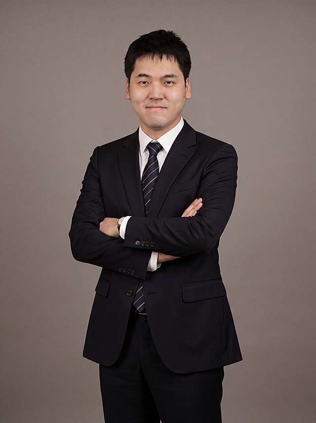 参考图中保留人物脸型、发型、年龄等特征生成职场全身形象照,标准焦段50mm,f/4光圈(f/2.8-f/4区间),平视视角(镜头与人物视线齐平);人物占画面合适比例,人物居中(居中构图),位于画面中心,为视觉聚焦点,全身照, 展现人物完整身形;上下留适量背景空间;头部与画面顶部保留合适空间;头身比例协调,人物结构准确;身穿深黑色精纺羊毛混纺西装外套,(平驳领设计,面料呈细腻微微哑光质感);内搭白色高支精梳棉衬衫;系着藏青色带细条纹真丝领带;下装深黑色精纺羊毛混纺西裤;着装正式干练;专业稳重;身形匀称,姿态端正,身体挺拔。呈双手抱胸的自然站姿，肢体放松且自信;佩戴精致配饰;发质微微柔顺，微微蓬松。简约微微暖调中性灰纯色背景(呈现均匀柔和质感),背景光线均匀柔和,强化色彩对比的高级感,极简干净;画质超高分辨率、细节清晰,现代精致感风格;肤质精细化处理;眼神直视镜头,目光坚定且澄澈,表情自然。嘴角上扬;肤质自然细腻,肤色健康均匀,皮肤状态清爽干净,保留真实皮肤细节｡正面柔光补光,4800K中性光,面部光比1:1.5｡中近景写实摄影,对焦清晰,面部雾面柔光,轻透裸肌感,高清保留皮肤细节｡分辨率4K,去除人物之外的所有元素。严格按照图片内容生成。画面比例3:4