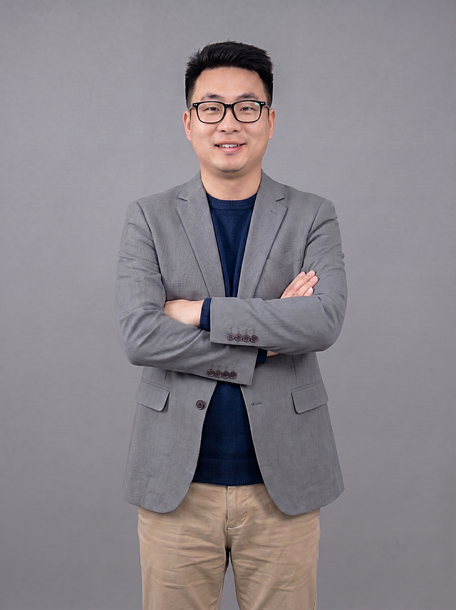 参考图中保留人物脸型、发型、年龄、灰色西装外套、深蓝色针织内搭、卡其色休闲裤、双手抱胸站姿、中性灰背景不变，保留人物原有黑框眼镜，保持专业情感咨询师形象，整体风格统一，画质4K，细节清晰，保留原照片光影和质感，去除所有配饰，画面比例3:4