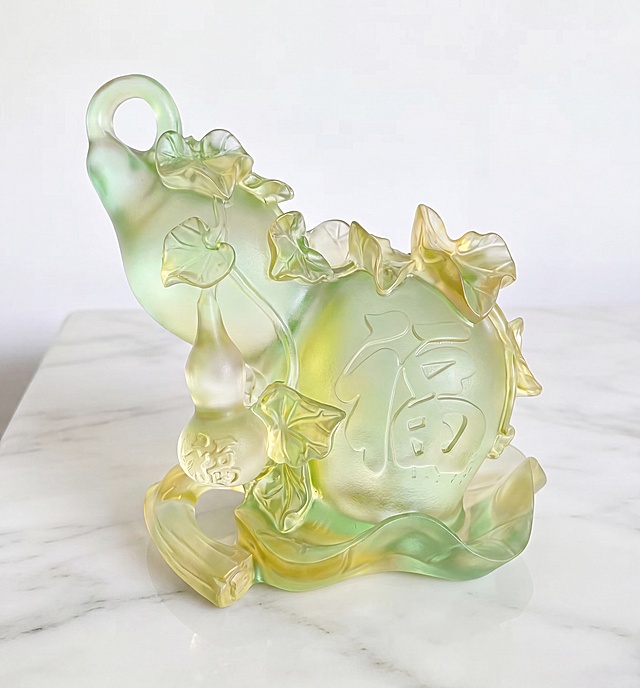 参考第二张摆件的通透浅绿黄色调，修改图1中琉璃葫芦摆件，让整体材质更加通透，保持原有造型和白色大理石桌面背景不变